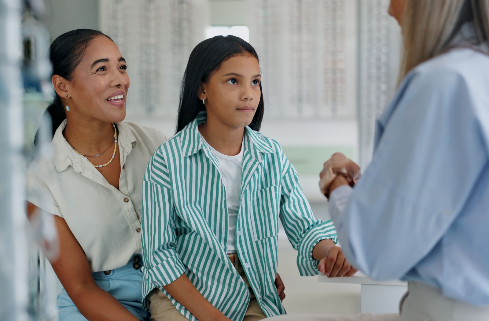 A parent smiling as they sit with their child and talk to their eye doctor about OHIP coverage.