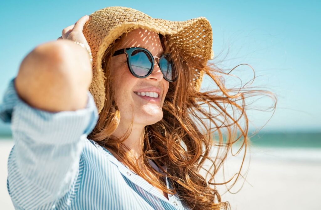 A person wearing sunglasses and a wide-brimmed hat at the beach to help prevent macular degeneration.