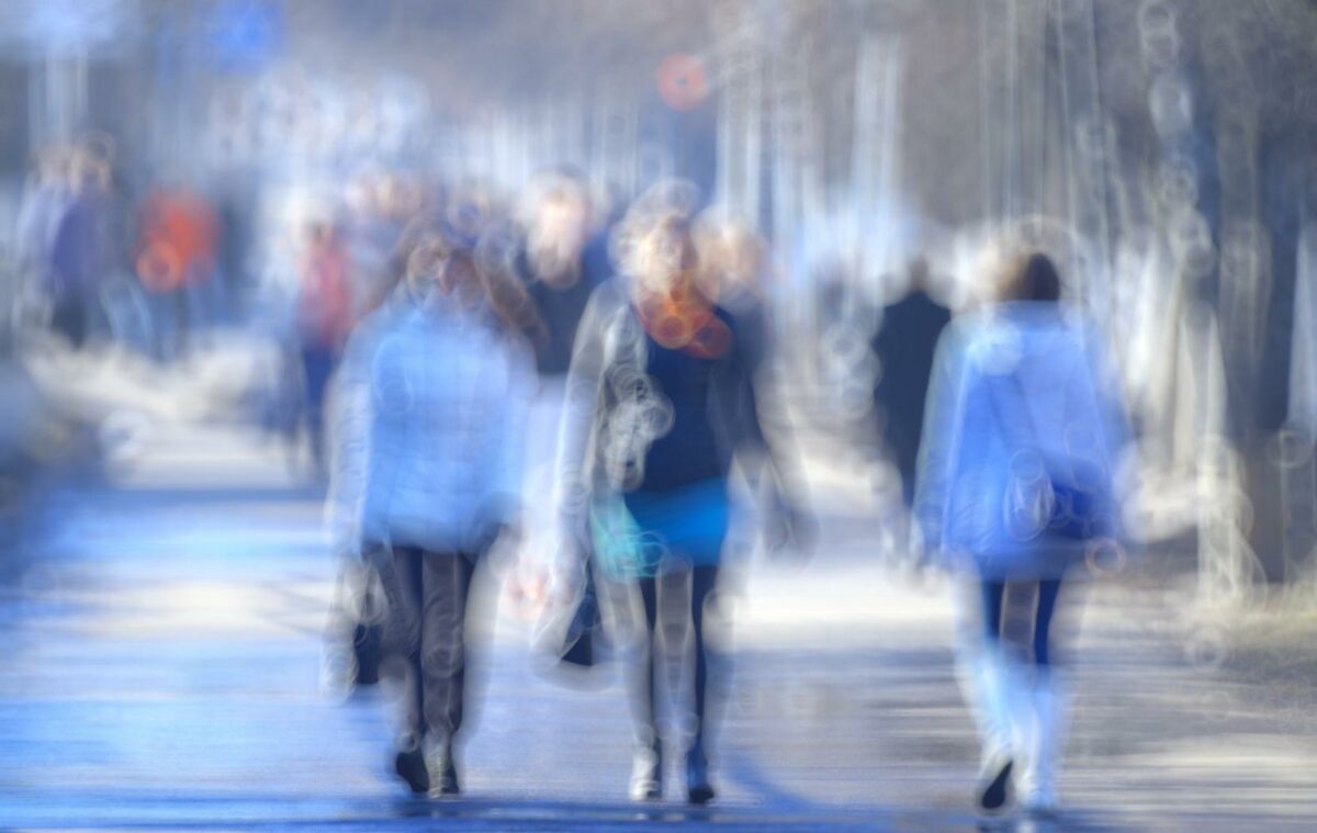 Blurry view of people walking outdoors, simulating impaired or distorted vision.